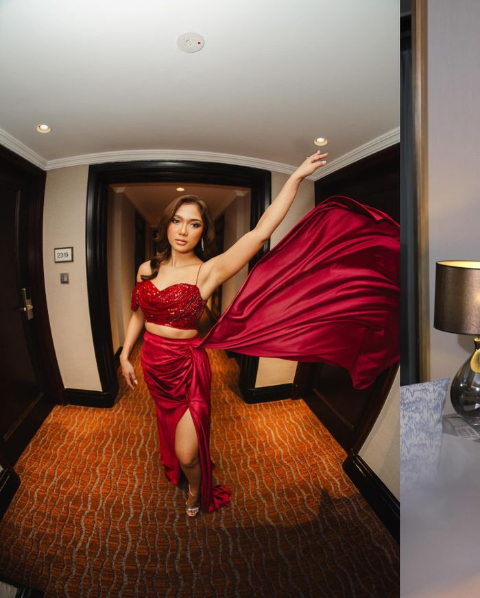 Marion Jola mengenakan gaun merah glamor dengan potongan high slit dan detail payet, dipadukan dengan tatanan rambut long wavy dan makeup glowing.