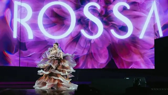 Rossa tampil memukau di atas panggung dengan gaun couture berlayer dramatis berwarna floral yang megah, rambut sleek updo, dan riasan panggung flawless.