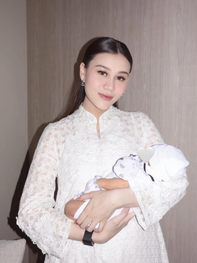 Dress tersebut memiliki potongan lengan panjang dan kerah shanghai, dihiasi bordiran halus yang memperkuat kesan feminin dan klasik.