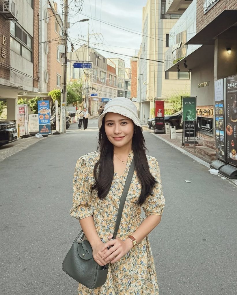 Prilly Latuconsina tampil kasual dengan floral dress warna kuning dan topi bucket saat jalan-jalan di Korea