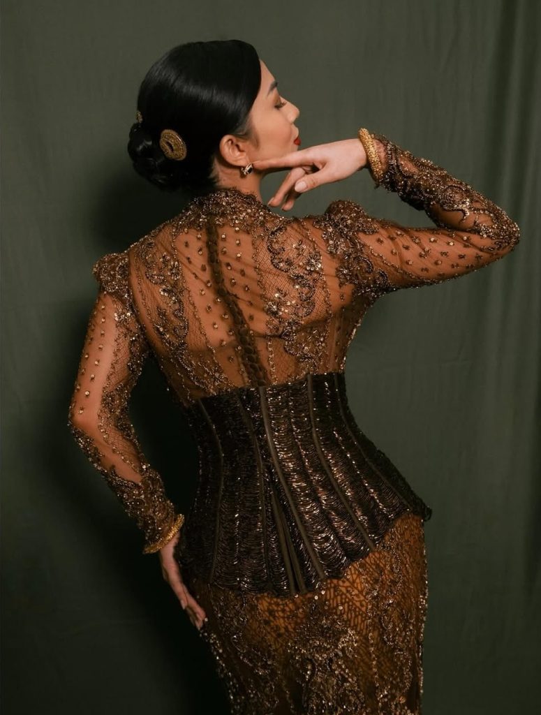 Tampak belakang kebaya Ariel Tatum menampilkan detail bordir rumit dan kain batik Udan Liris, dengan rambut disanggul dan aksesori emas klasik.