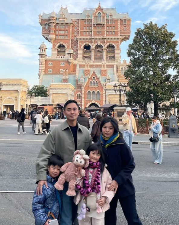 Cindy dan keluarga di depan Tower of Terror Tokyo DisneySea dengan anak memeluk boneka.