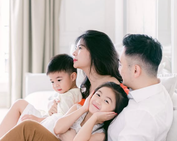 Cindy dan keluarga santai duduk di sofa dengan nuansa putih dan lembut.