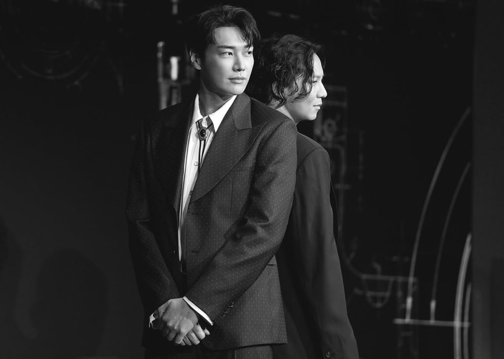 Kim Young-kwang sebagai Moon Baek yang berdiri tenang, menggambarkan aura misterius sang broker senjata.