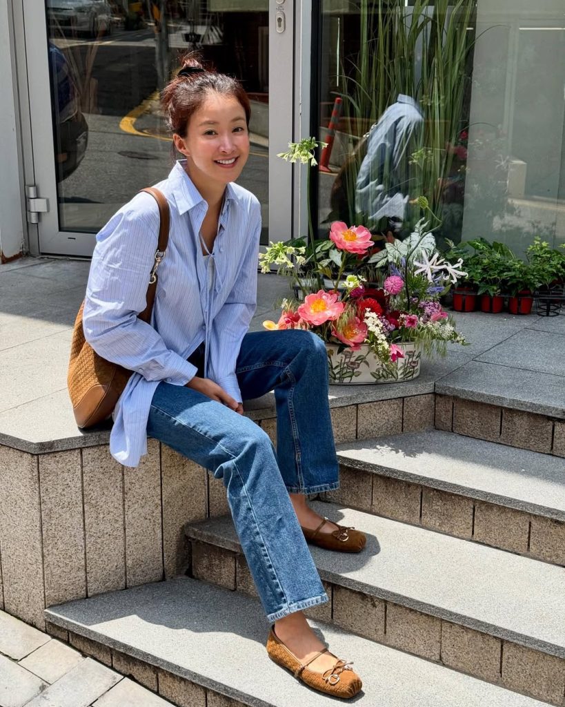 Lee Si Young dengan kemeja biru longgar yang dipadukan dengan jeans lurus berwarna klasik.