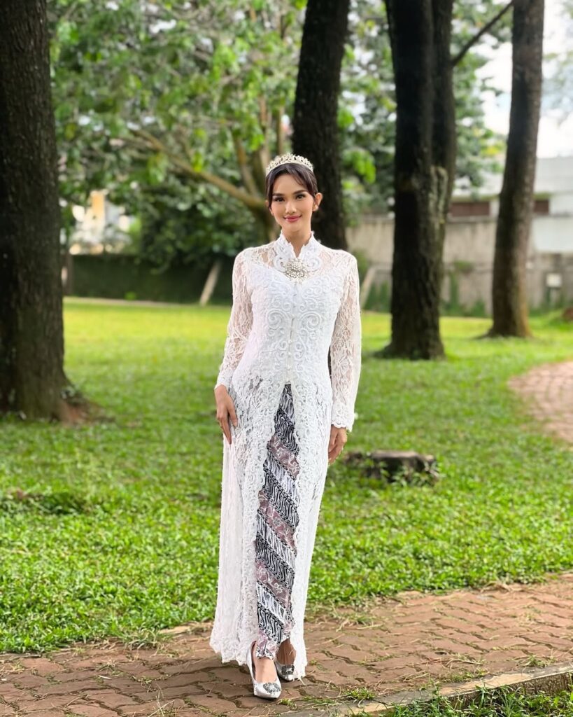 Terlihat penampilan utuh Faby Marcelia dari kepala hingga kaki. Kebaya putih panjang dengan belahan di bagian depan memperlihatkan kain batik yang terbalut indah.