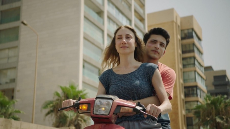 Arzé dan Kinan menaiki skuter di jalanan Beirut dengan latar gedung tinggi, mengambarkan semangat pencarian dan dinamika ibu-anak yang emosional.