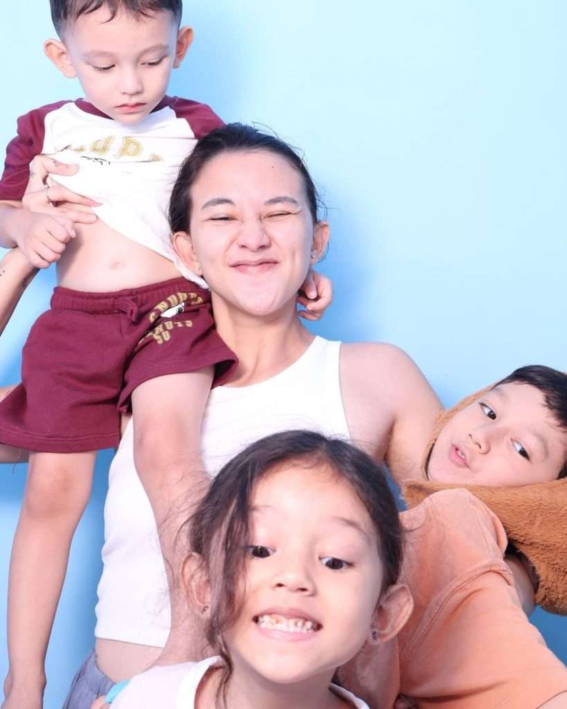 Dahlia Poland dan ketiga anaknya hangat bersama di tempat tidur.