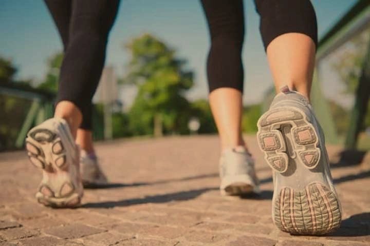 Ilustrasi kaki melangkah di jalur pedestrian saat matahari terbit, menggambarkan rutinitas jalan pagi yang konsisten.