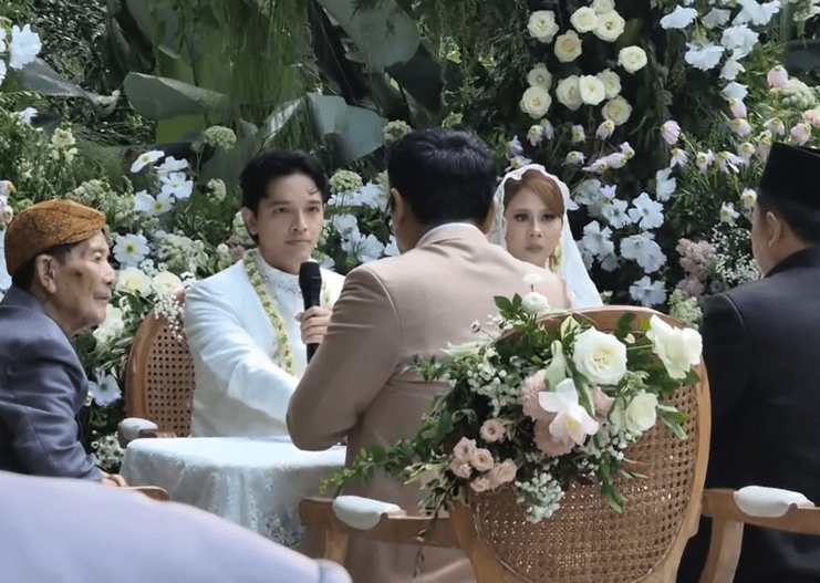 Penampilannya dilengkapi dengan veil renda panjang dan untaian melati di sisi kanan, simbol kesucian dan keharuman hati.