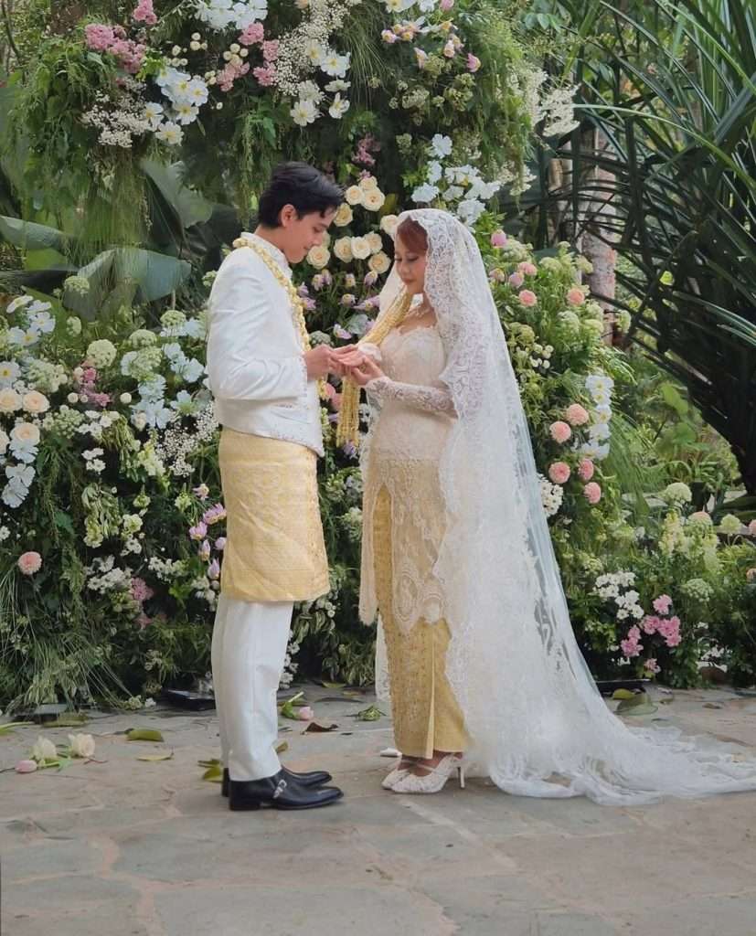 Prosesi ijab kabul berlangsung di tengah alam terbuka yang asri, dikelilingi pepohonan dan dekorasi bernuansa earth tone.