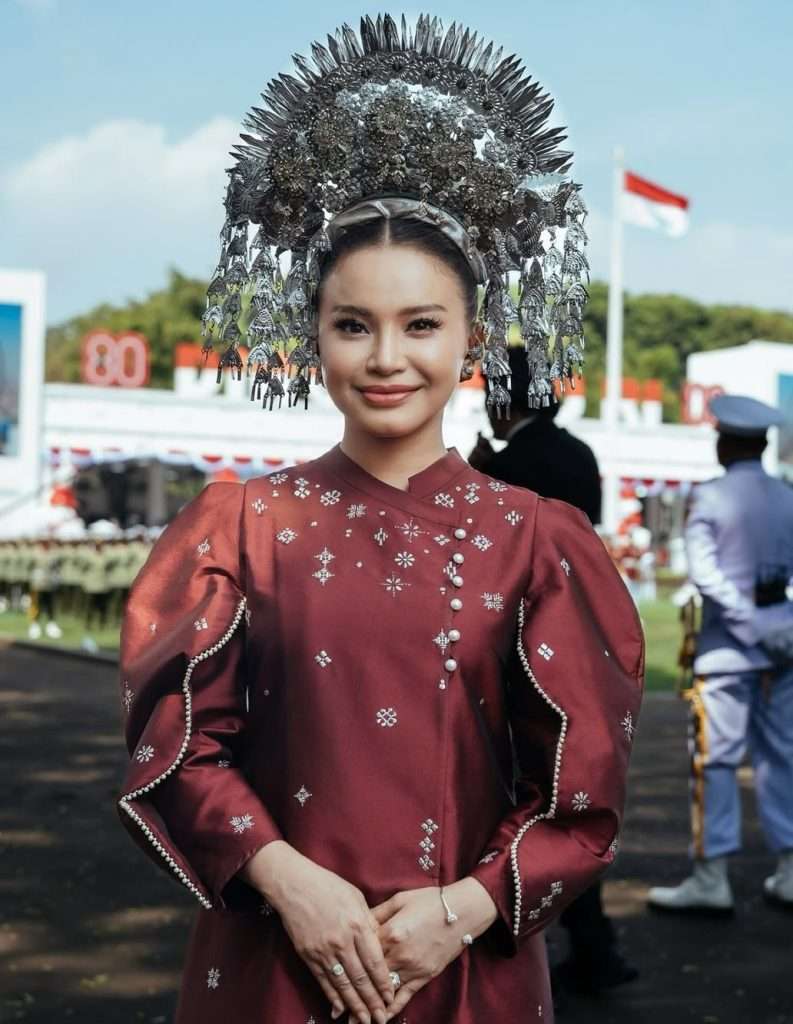 Busana adat Rossa warna merah marun dengan hiasan tradisional