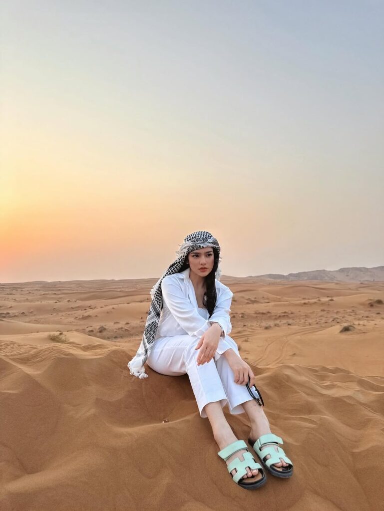 Davina juga sempat menikmati safari gurun Dubai. Di tengah hamparan pasir yang luas, ia tampil serba putih dengan crop top, celana panjang, dan kemeja longline.