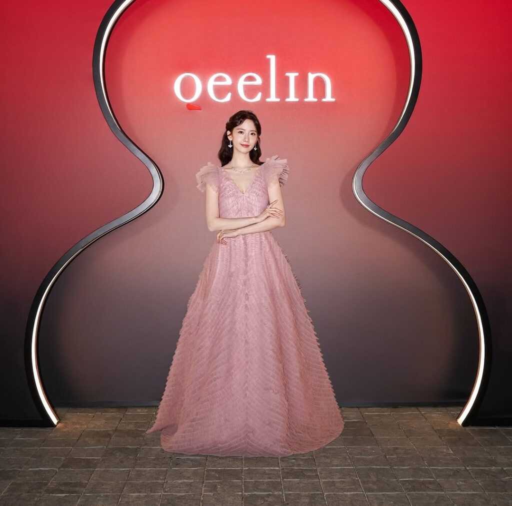 Siluet gaun berbentuk A menonjolkan kesan manis, sementara rambut ikal tipis menambah nuansa romantis. Aksesori minimalis membuat Yoona tampak seperti putri modern.