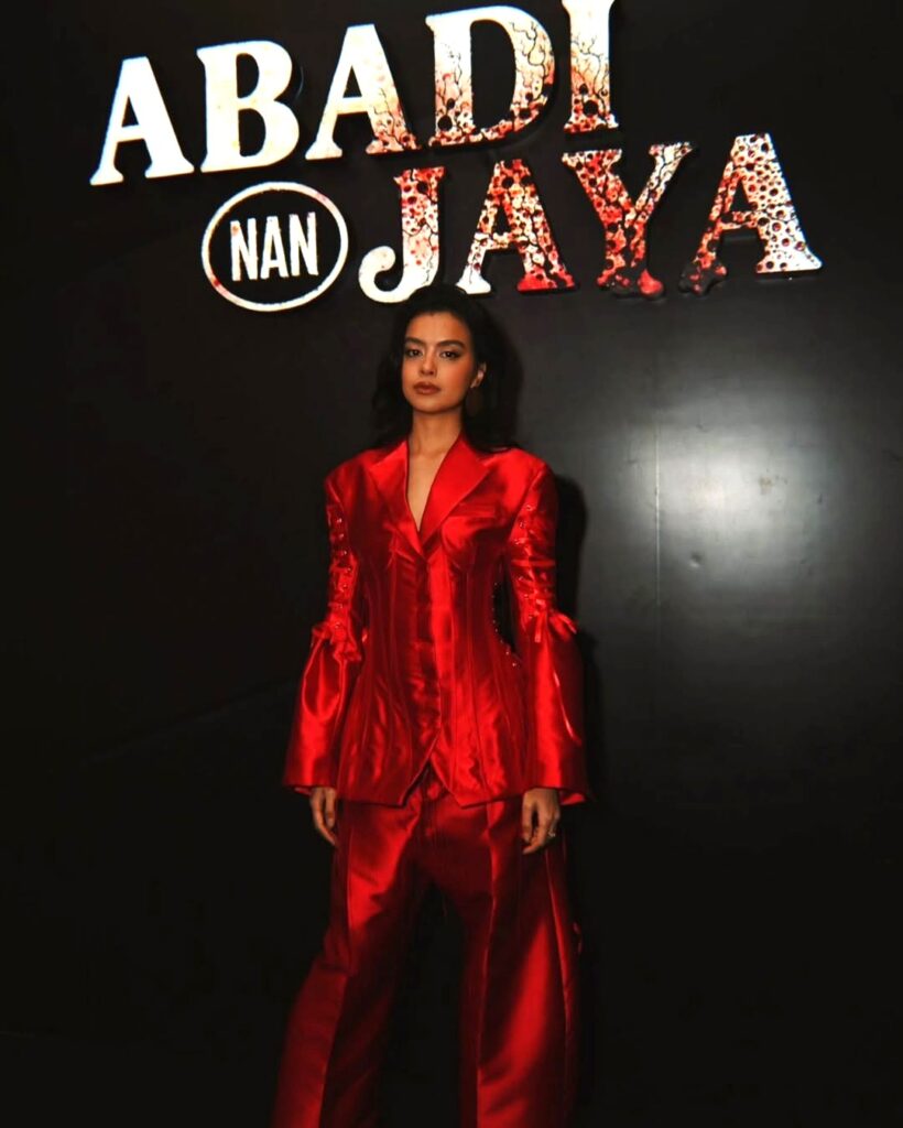 Warna merah yang dikenakan Eva bukan hanya elemen visual, tetapi juga simbol dari energi, passion, dan karisma yang telah menjadi ciri khasnya dalam setiap karya dan penampilan publik.