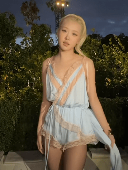 Romper lingerie yang dikenakan Rose hadir dengan detail renda halus dan aksen pita panjang yang menyapu lantai, menciptakan kesan dramatis namun tetap lembut.