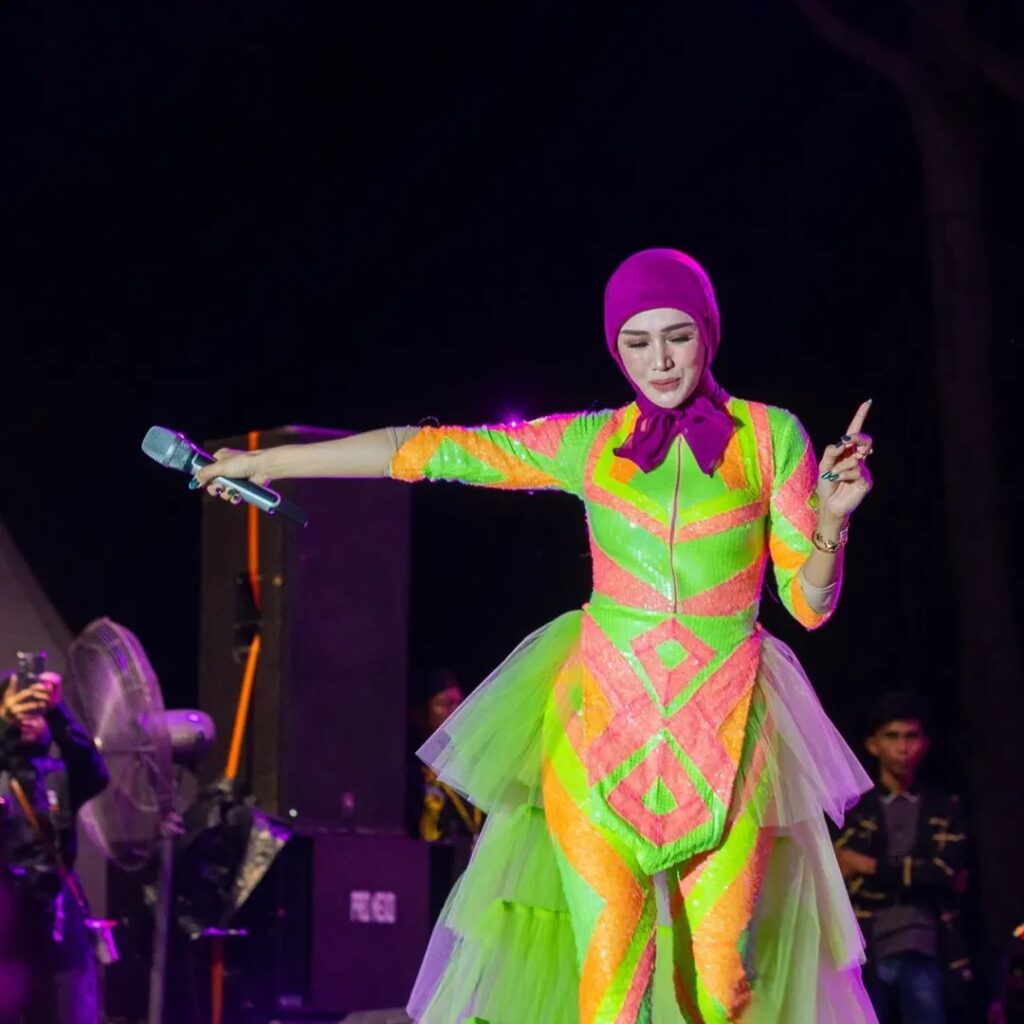 Mulan memilih hijab segiempat dengan ciput berwarna ungu tua, lalu menambahkan simpul pita besar di bagian leher.