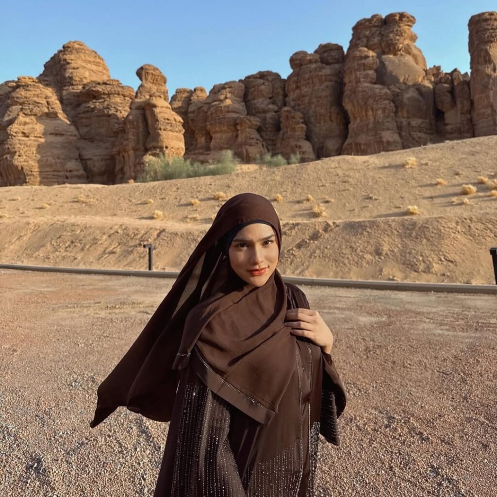 Davina Karamoy mengenakan hijab cokelat di tengah lanskap gurun