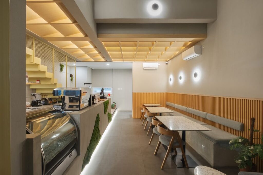 Saat melangkah masuk, pengunjung langsung disambut oleh elemen dramatis yang menjadi jantung dari desain kafe ini